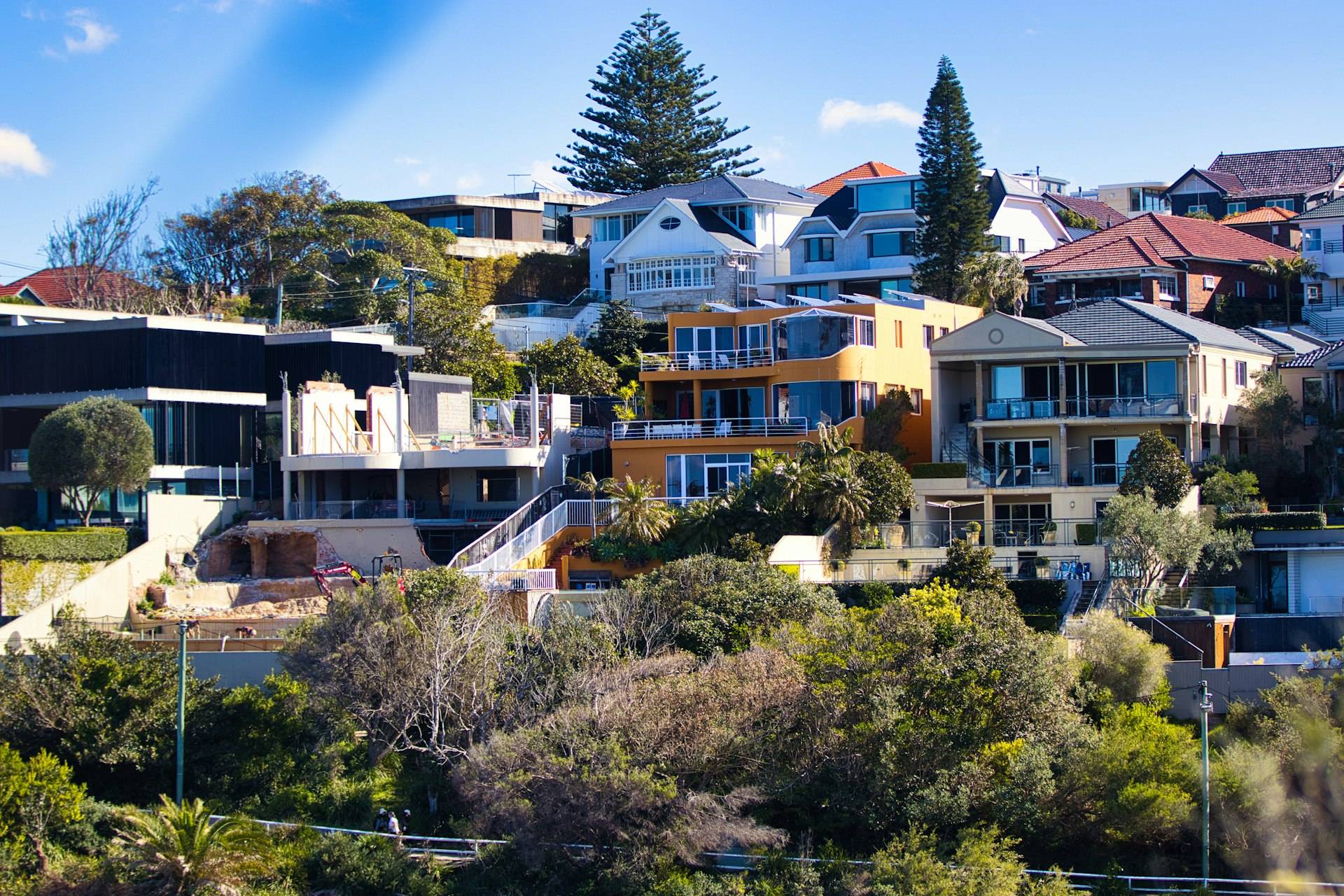 Houses stepping down a green Sydney hillside toward the water