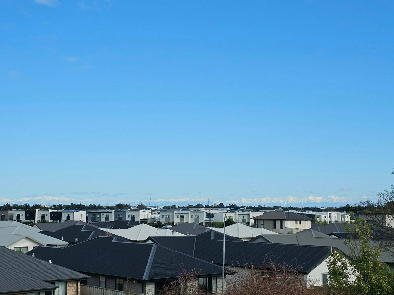 Rooftops of a Christchurch subdivision with the Southern Alps in the distance