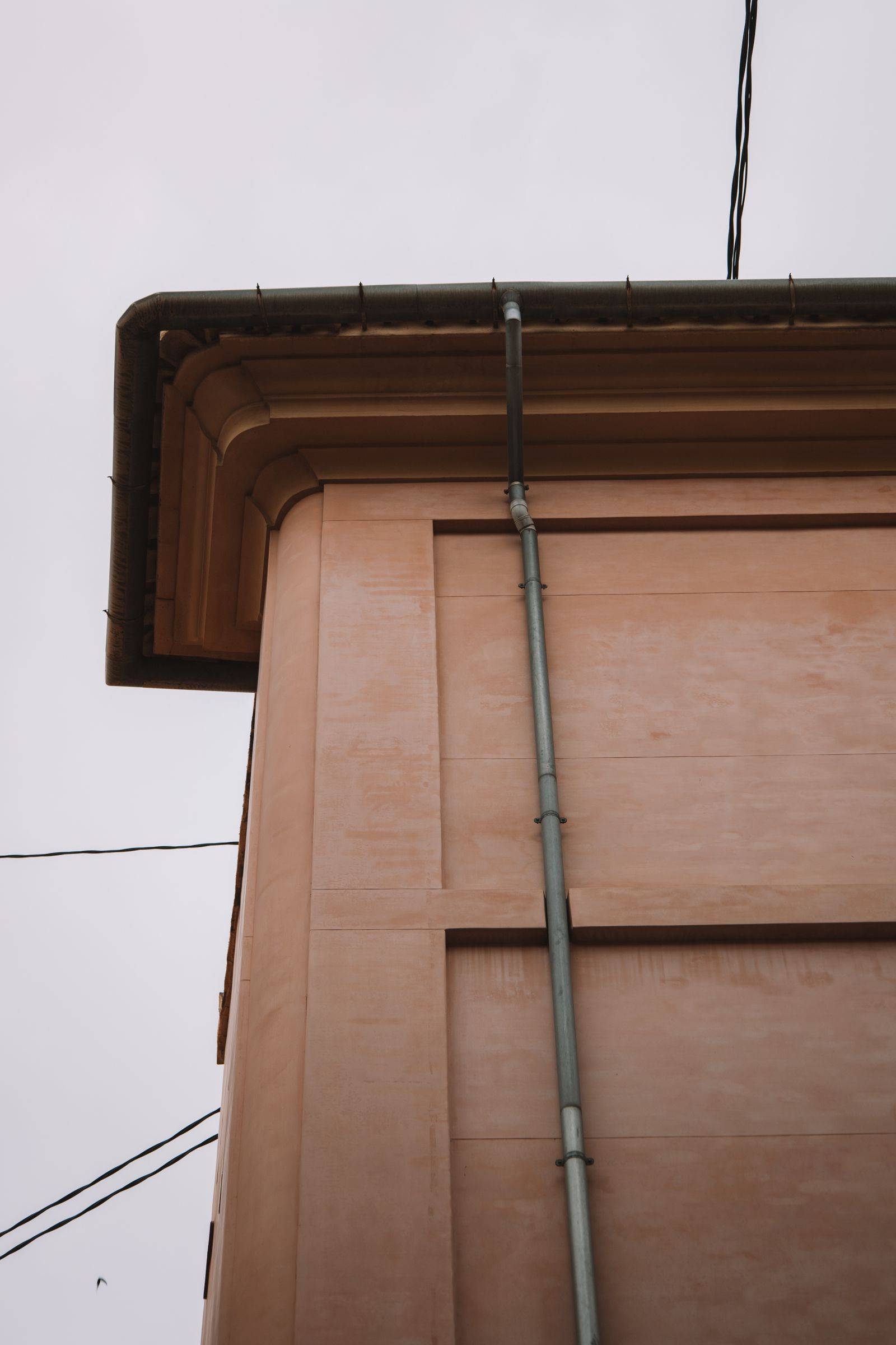 A building corner showing the fascia, gutter, and downpipe joined together