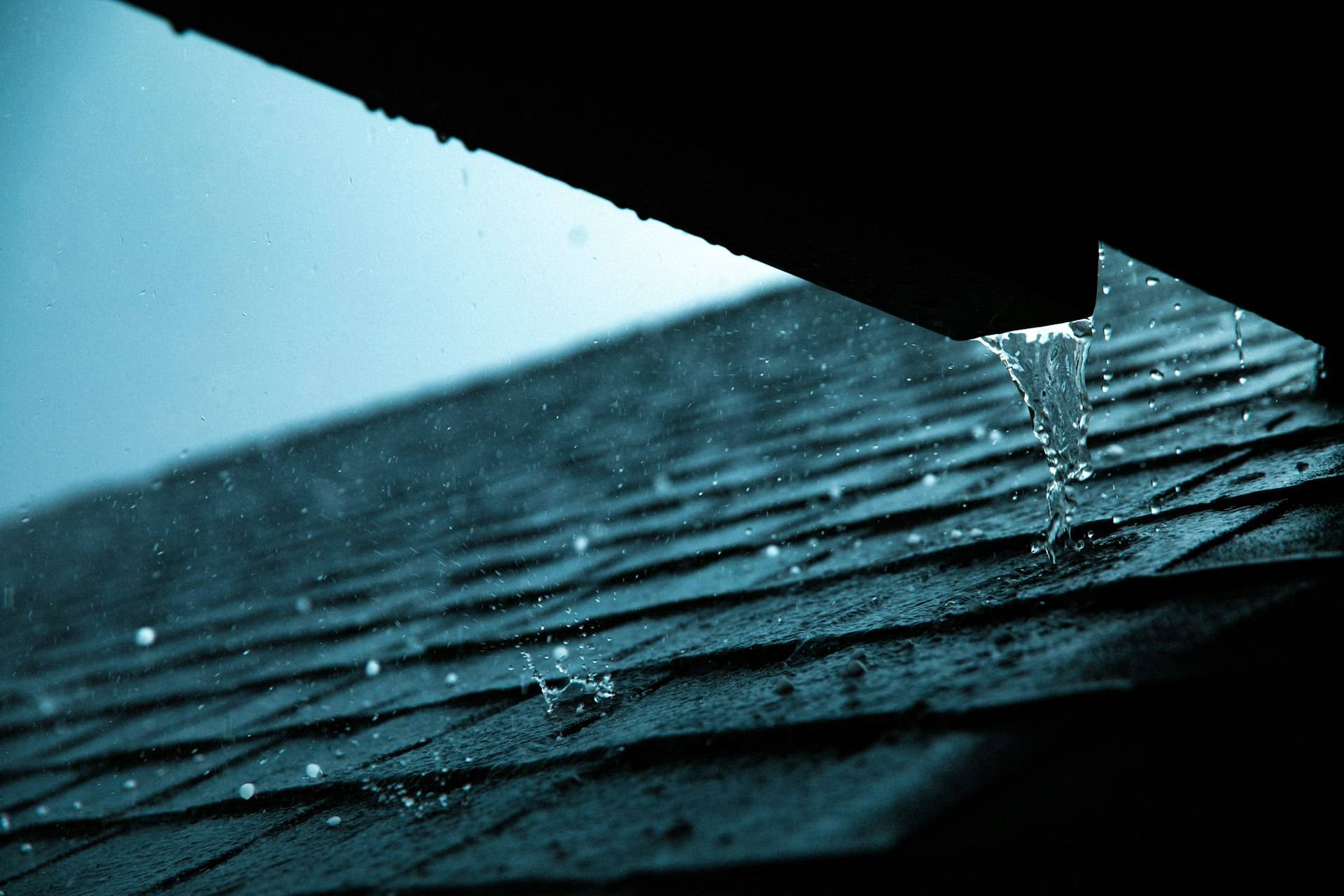 Rainwater draining off a gutter edge during a downpour