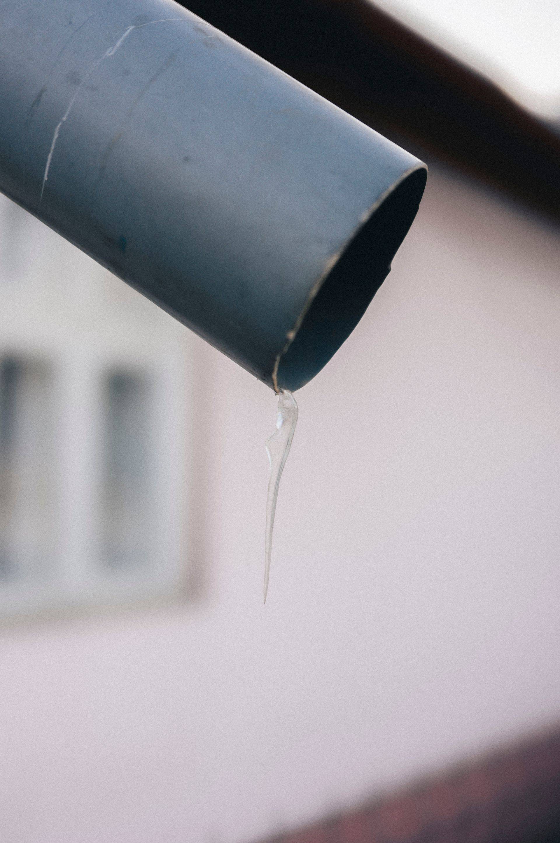 A small icicle forming at a downspout outlet in freezing weather