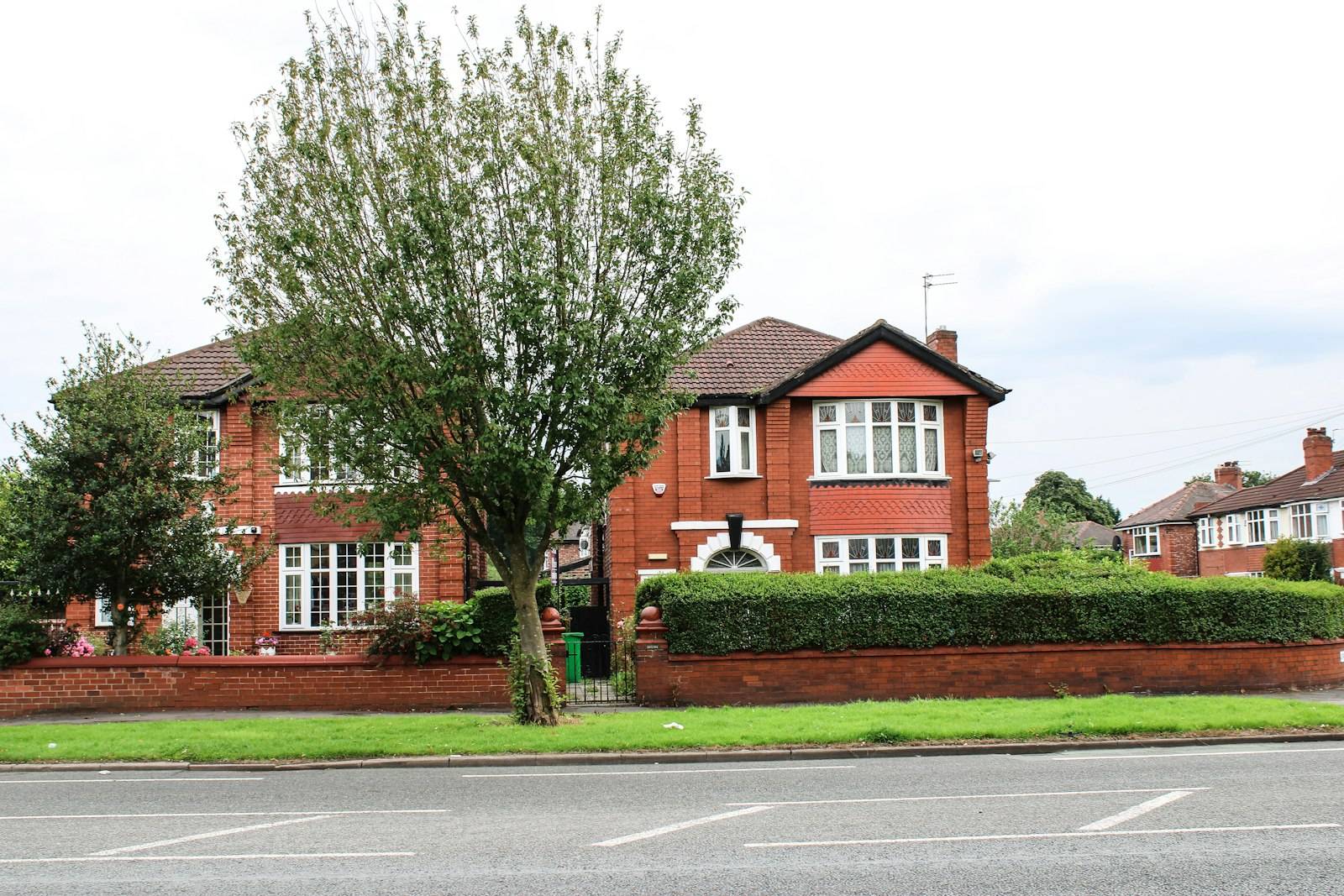 A red-brick suburban semi-detached house with bay windows in Manchester