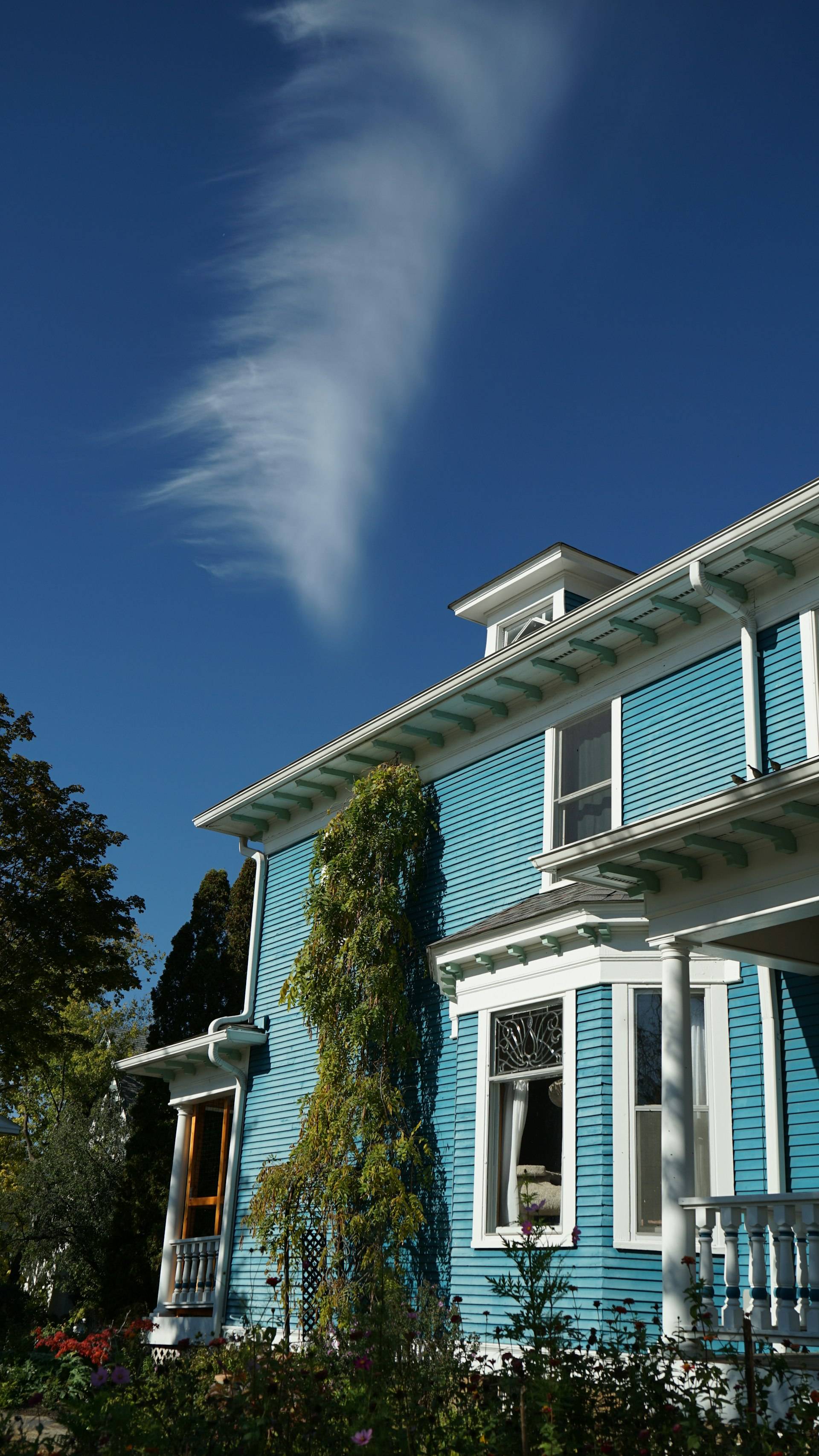A teal Victorian house with white trim under a blue sky in Minneapolis