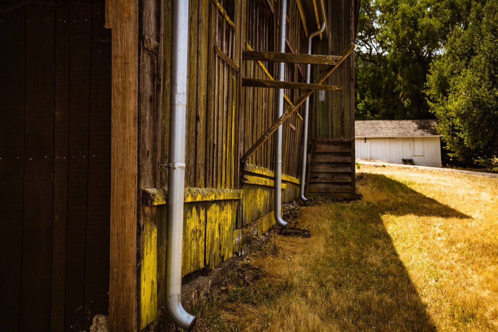 New aluminum downspouts installed against a weathered barn wall