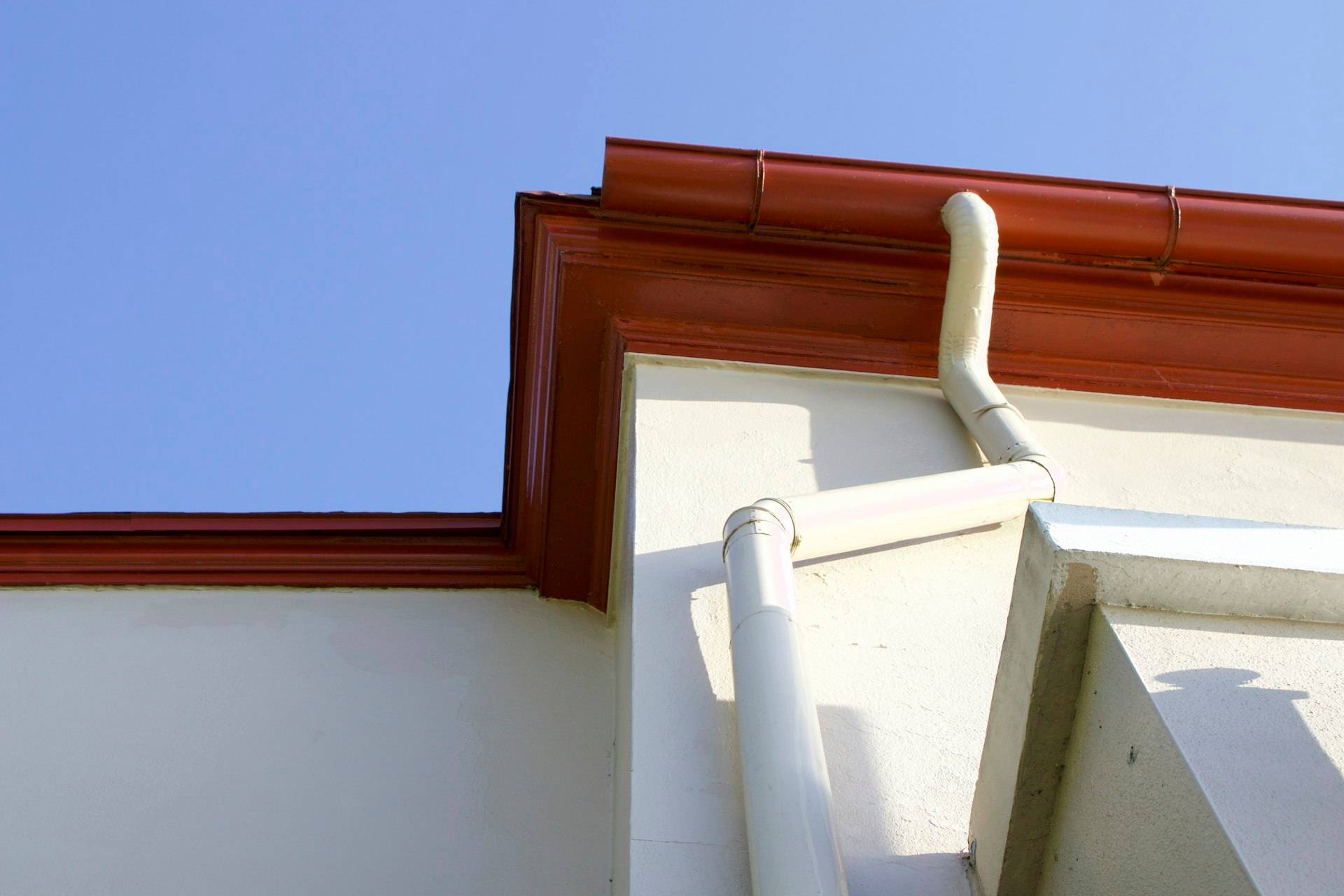 A clean, newly painted gutter and downspout corner on a house exterior