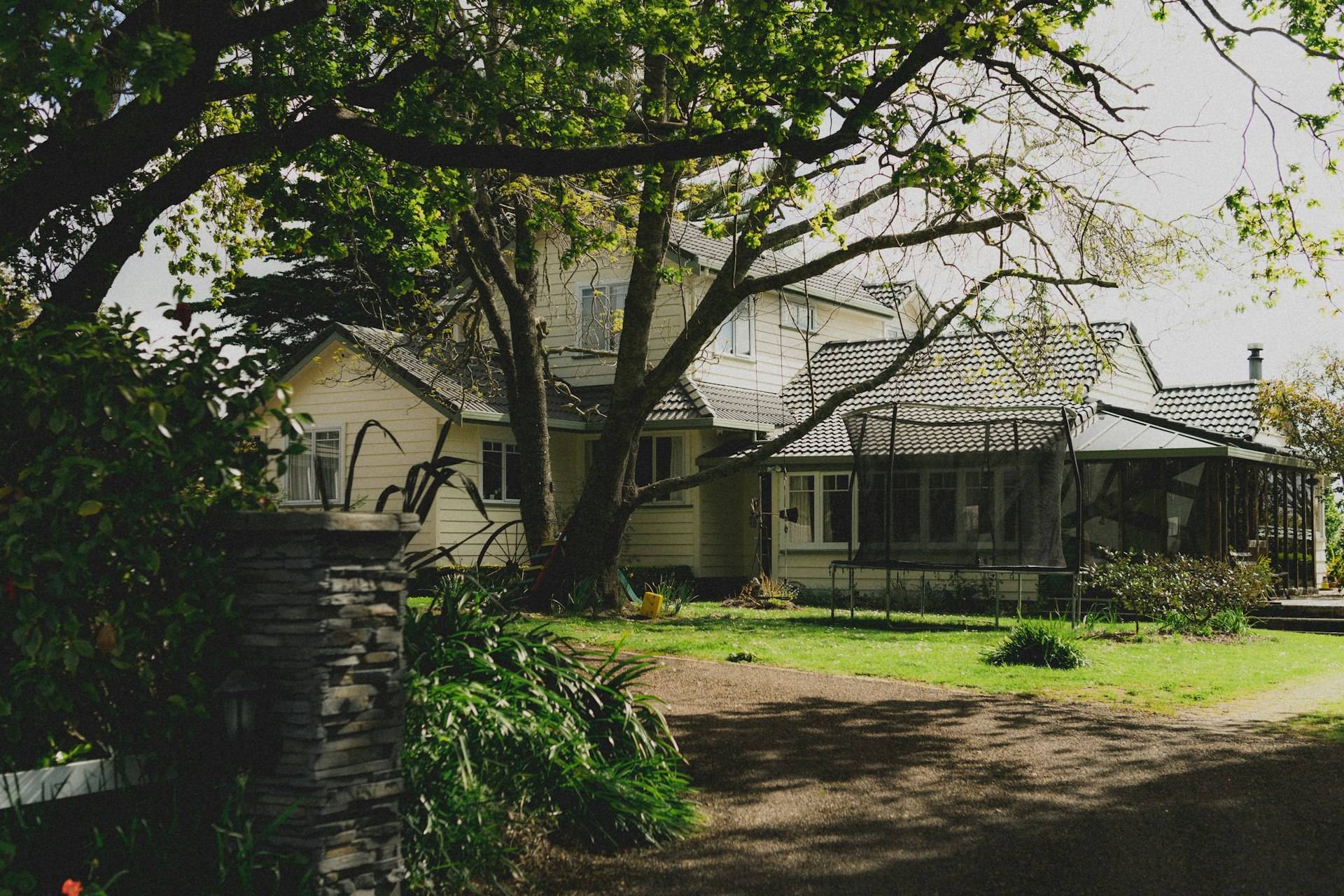 A New Zealand villa with a wraparound verandah shaded by a large oak tree