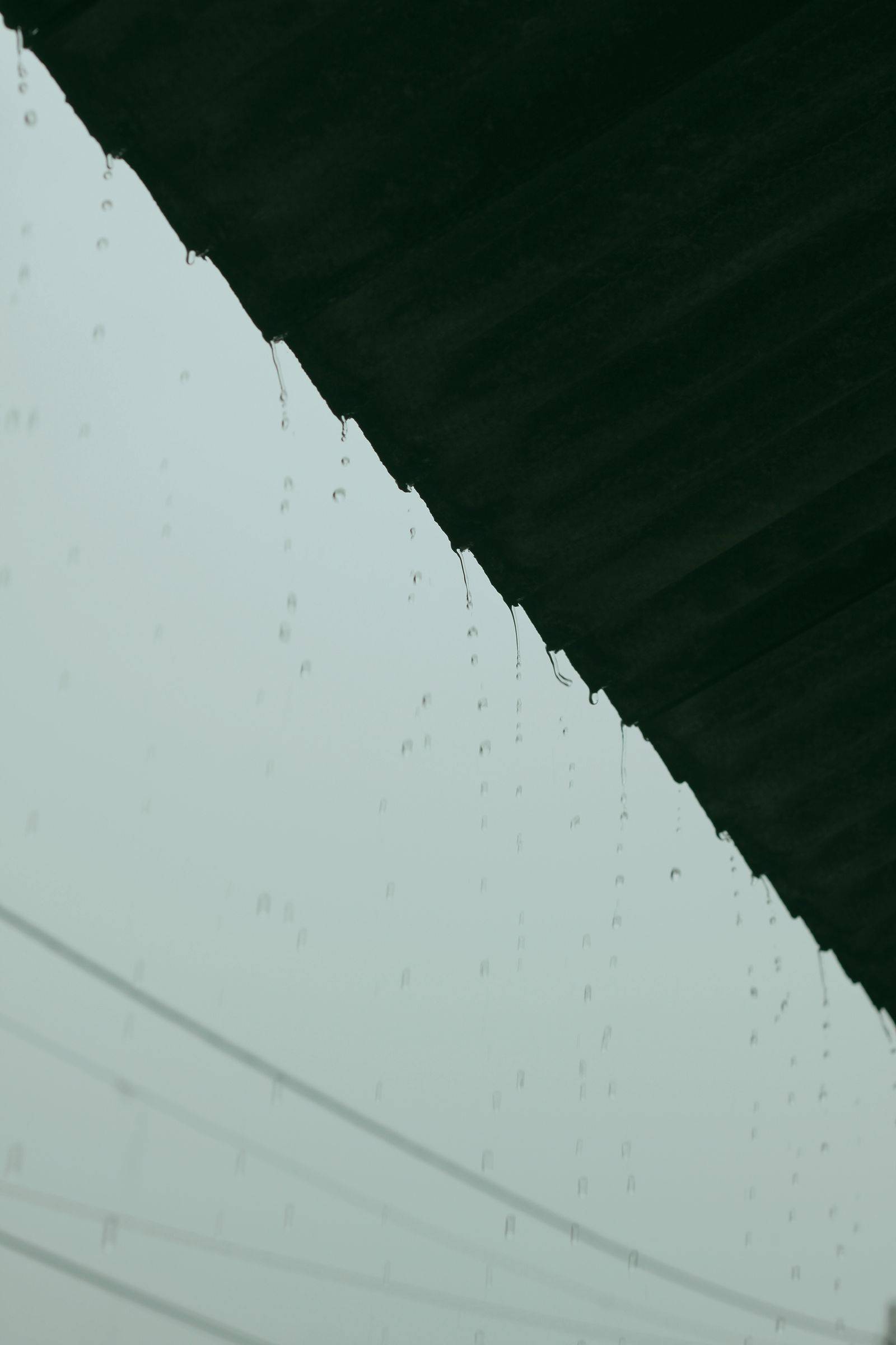 Rain dripping directly off a bare roof edge with no gutter installed