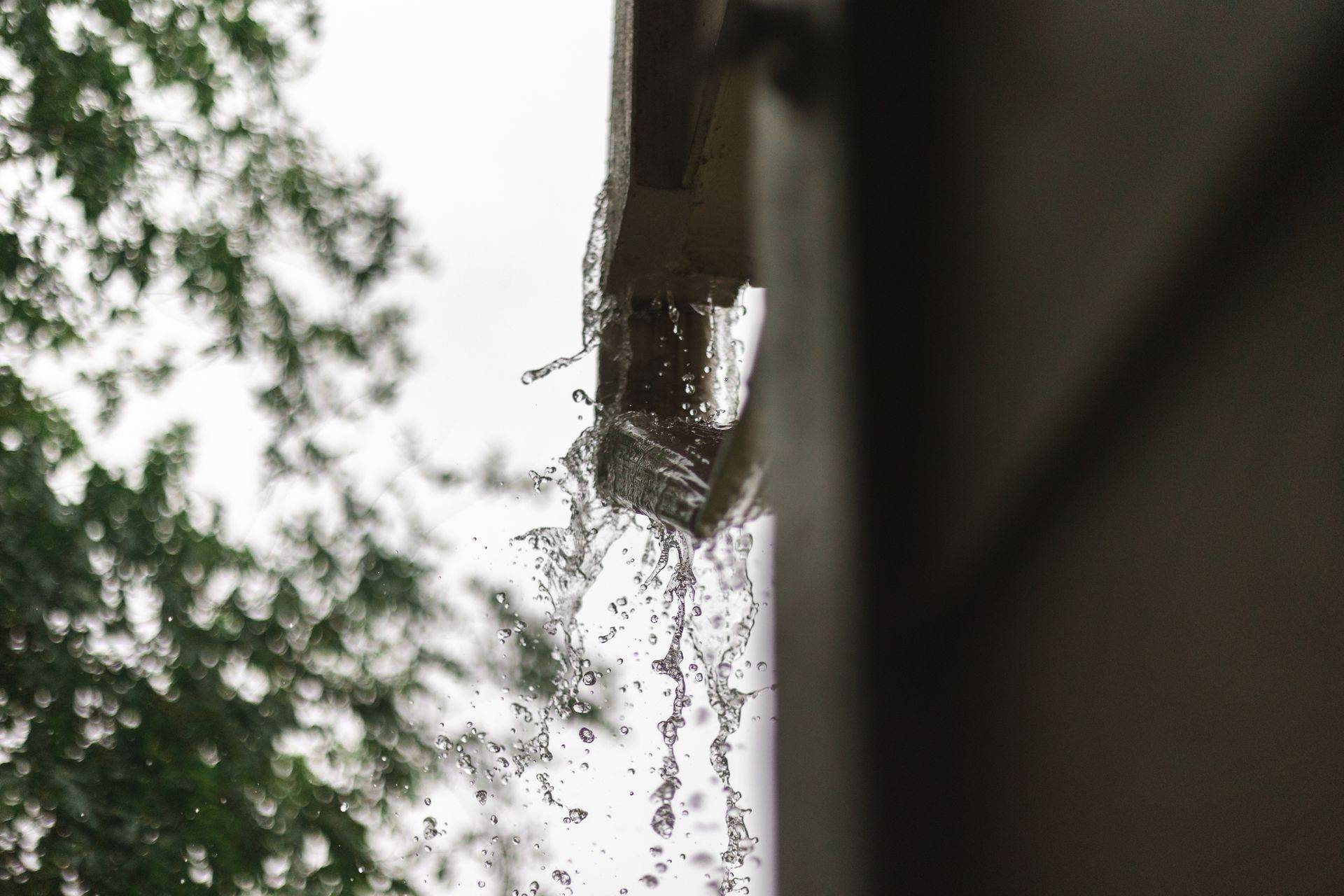 Rainwater overflowing from a gutter corner during heavy rain