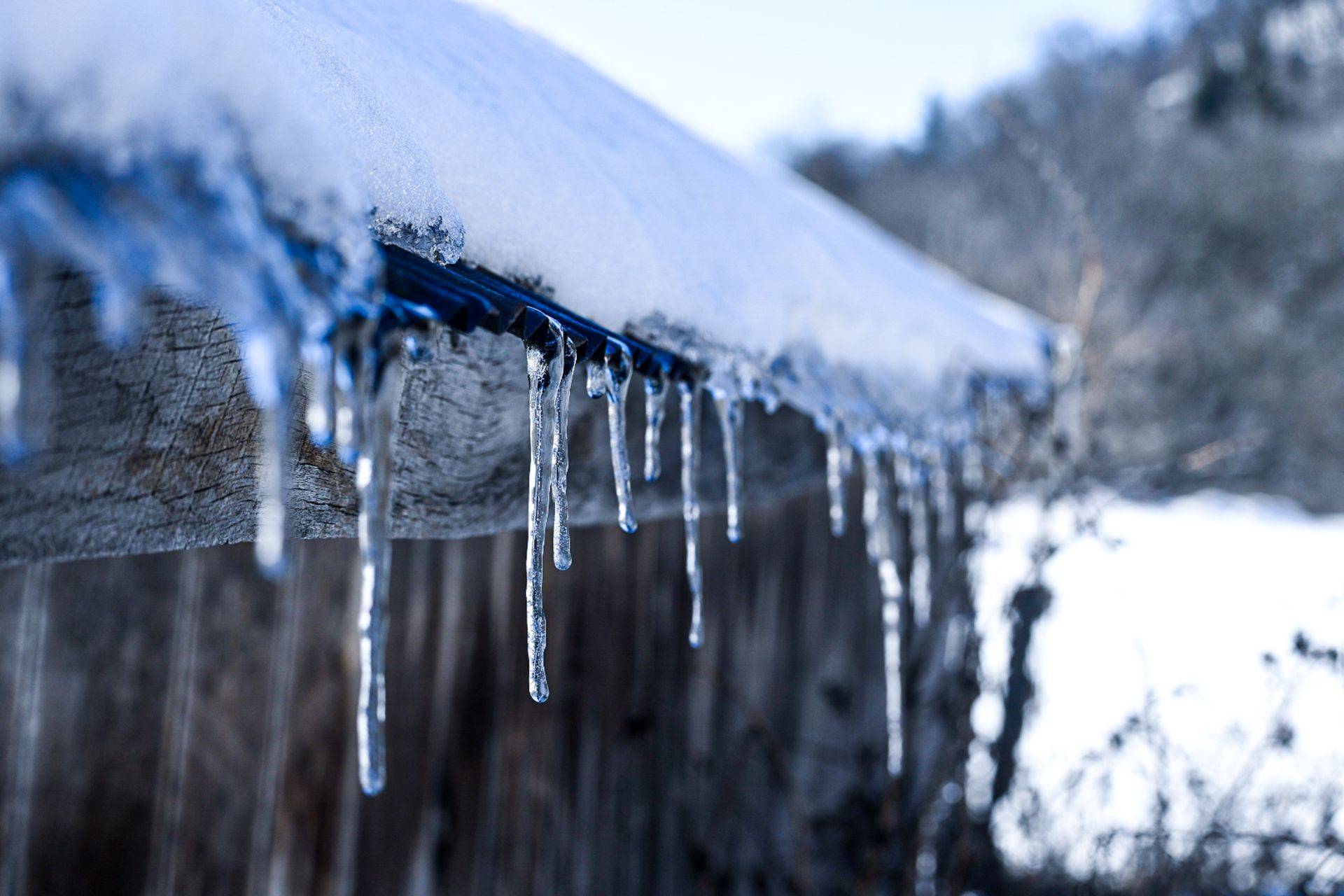 Icicles hanging along a snow-covered roof edge in winter