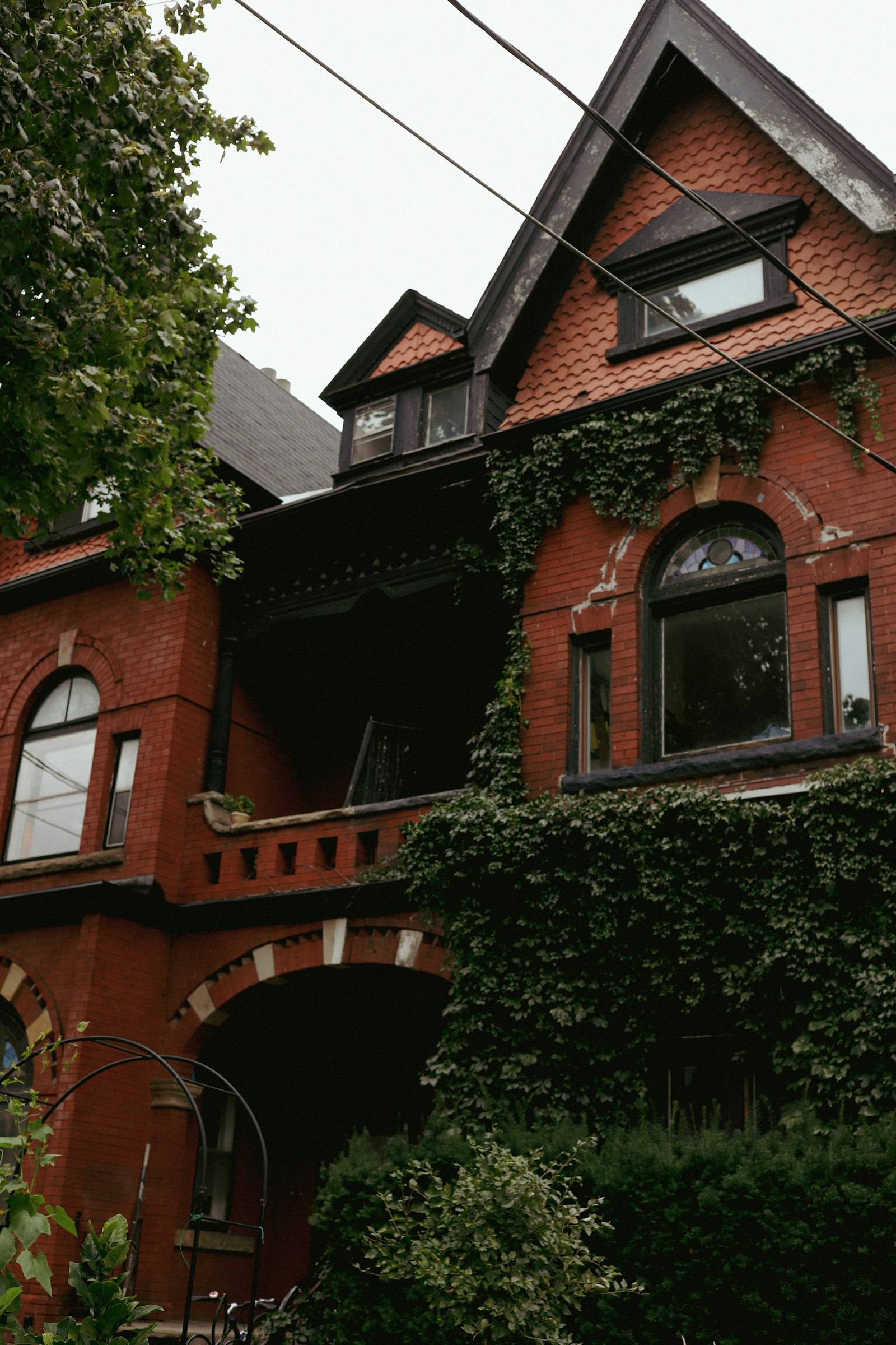 A red brick Victorian house covered in ivy with a stained-glass window in Toronto